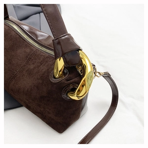 Detail of dark brown suede shoulder bag with glossy leather and gold chain link