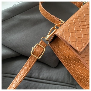 Gros plan d'un sac à bandoulière tressé marron avec finitions dorées chic