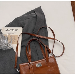 Close-up of retro brown quilted handbag with silver clasp on a grey blazer
