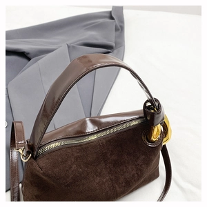 Detailed close-up of dark brown suede and smooth leather texture with gold metal buckle