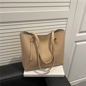 Minimalist beige PU leather tote bag with gold logo on white art books