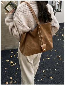 Detail of caramel suede tote bag with mini coin purse on shoulder during autumn
