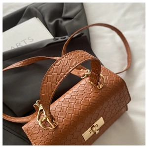 Détail du sac à main marron avec texture tressée et fermoir en métal doré brillant