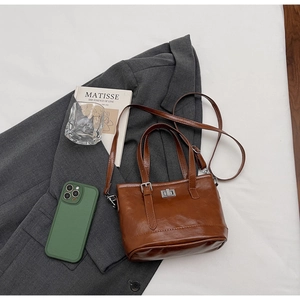 Detail of vintage brown leather bag with silver metal twist lock on a grey suit