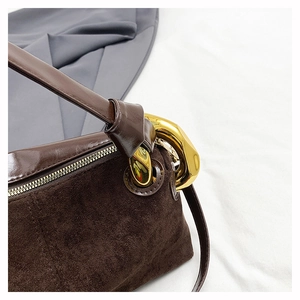 Detail of dark brown suede shoulder bag with oversized gold metal buckles and zipper