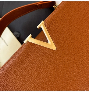 Détail du sac à main en cuir marron avec logo en métal doré en forme de V élégant