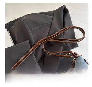 Detail of blue denim and brown leather handbag with gold buckles and dual shoulder straps