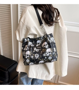 Detail of a large tote bag featuring white skull and floral print with chain strap