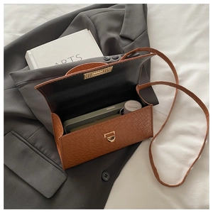 Détail de l'intérieur du sac bandoulière marron tissé contenant smartphone et cosmétiques