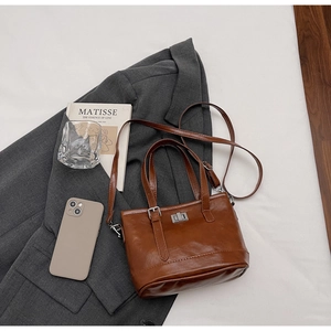Macro detail of brown quilted leather handbag with silver clasp on a stylish suit
