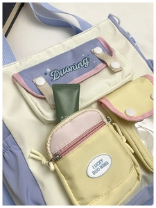 Detail view of multi-pocket canvas crossbody bag in pastel purple and cream