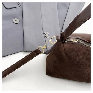 Detail of dark brown suede and leather splicing on shoulder bag with gold hardware