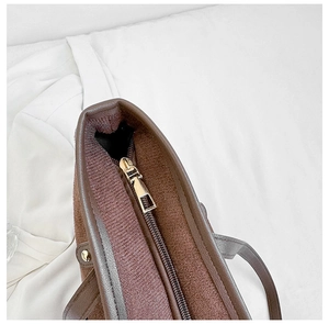Close-up of brown textured fabric tote with light gold zipper and grey leather trim