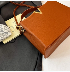 Gros plan d'un sac cabas en cuir grainé marron caramel avec ornement élégant en V doré