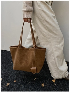 Close-up of a large brown suede tote bag featuring slim double shoulder straps and detail