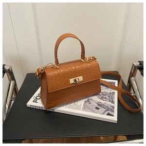 Détail du sac à main en cuir marron avec texture serpent et fermoir doré rotatif