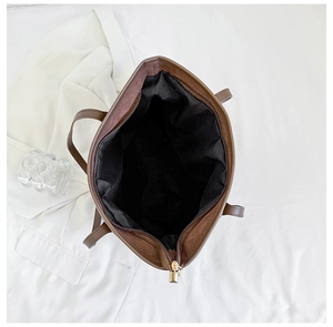 Top-down view of a spacious brown tote bag with black lining and gold zipper detail
