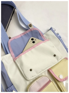 Detail view of multi-pocket canvas tote with metal buckles and colorful pastel sections