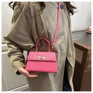 Détail d'un mini sac à main tressé rose avec fermoir rotatif doré et bandoulière fine