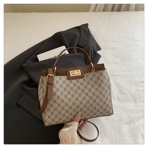 Gros plan sur un sac seau vintage avec motif monogramme et fermoir doré rotatif