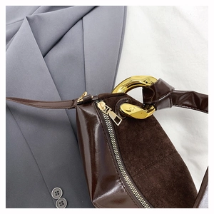 Detail of dark brown leather underarm bag with gold chain strap and suede texture