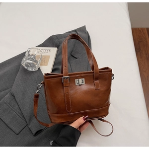 Detail of vintage brown leather tote bag with silver turn-lock and adjustable strap