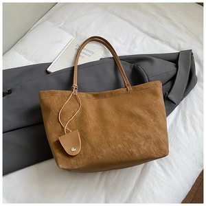 Detail of vintage brown tote bag with matte texture next to a grey suit and book