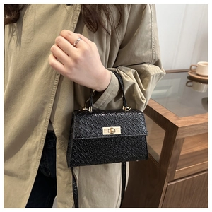 Gros plan d'un sac à main noir texturé avec fermoir doré sur une femme élégante