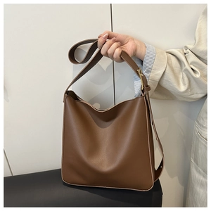 Detail of brown leather hobo bag featuring matte finish and adjustable strap with gold buckle