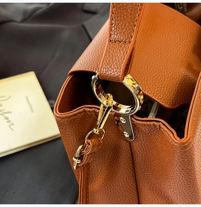 Détail d'un sac à main en cuir marron grainé avec boucles métalliques dorées et coutures