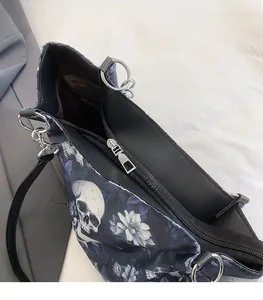 Detail of metal zipper puller on large tote bag with gothic skull and flower pattern