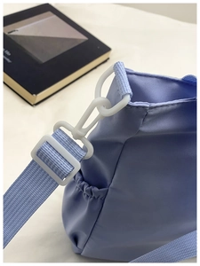 Detail of adjustable strap buckle and elastic side pocket on light purple nylon tote bag