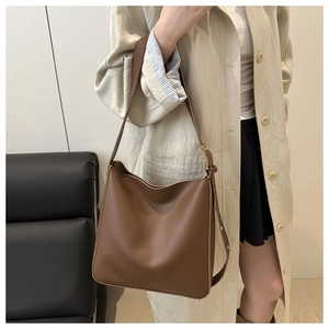 Detail of adjustable strap and bronze hardware on brown leather bucket bag