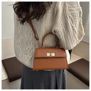 Détail d'un sac à main marron en cuir à motif litchi avec fermoir doré et bandoulière