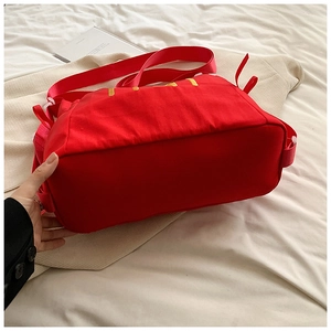 Detail der roten Canvas-Tasche mit gelber Stickerei und breitem Taschenboden