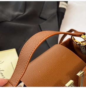 Gros plan sac en cuir marron grainé avec boucle en V dorée et détails strassés