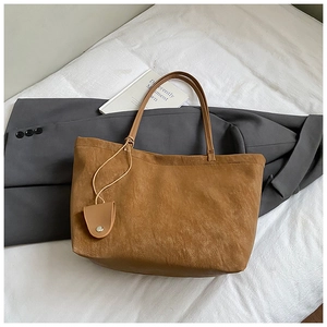 Detail of a brown suede tote bag with slim shoulder straps and a mini snap coin purse