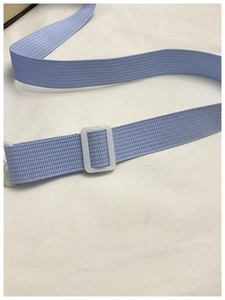 Detail of light blue nylon shoulder strap with white plastic buckle for student bags
