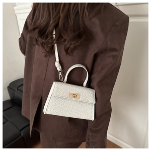 Détail du sac bandoulière blanc à texture crocodile avec fermoir rotatif doré chic