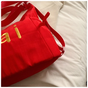 Detailansicht der roten Canvas-Tasche mit gelber Stickerei und verstellbarem Schultergurt