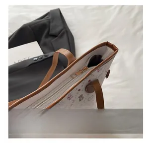 Gros plan du zip doré et du motif ours rose sur le grand sac cabas blanc pour femme