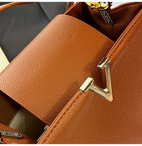 Gros plan sur la boucle en V dorée d'un sac à main en cuir marron grainé de luxe