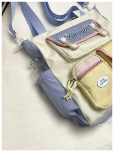 Detail of multi-pocket crossbody bag with side water bottle holder and wide blue strap