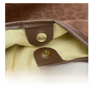 Detail shot of the golden magnetic closure on a leopard print tote bag with soft suede