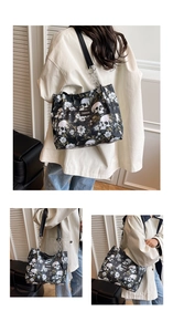 Detail view of large black tote bag with skull and floral print and chain strap