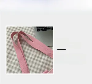 Detailed macro view of the comfortable pink woven strap handle on a canvas handbag