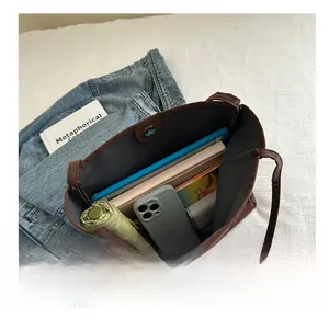 Interior storage capacity view of large brown tote bag with magnetic closure and daily items