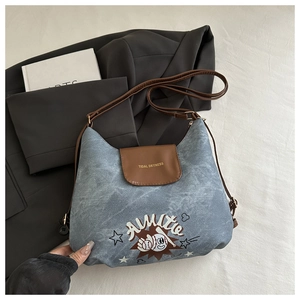 Dettaglio borsa a tracolla in denim con ricamo baseball e cinturino in pelle marrone
