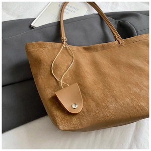 Macro view of brown leather tote bag texture and mini pouch detail on strap