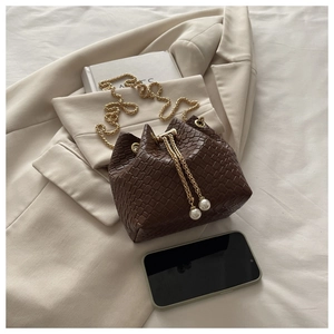 Dettaglio borsa a secchiello marrone scuro con trama intrecciata e perle eleganti